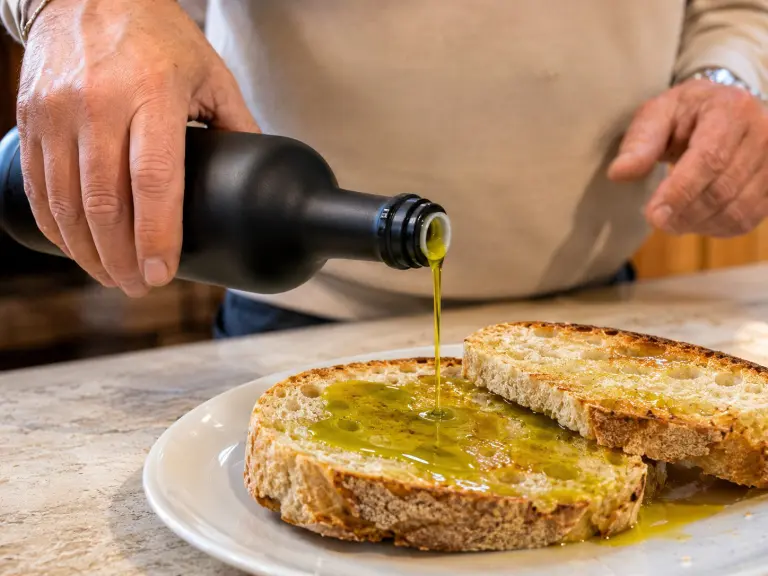 Olio extravergine umbro versato in una ciotola tra olive fresche