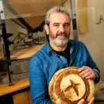 Davide Longoni nel laboratorio di Milano accanto al mulino a pietra installato per macinare il grano direttamente nel panificio