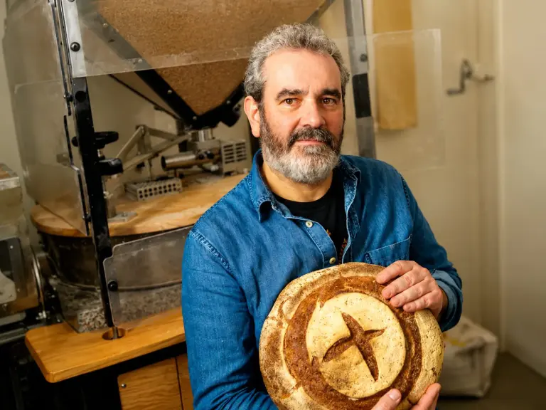 Davide Longoni nel laboratorio di Milano accanto al mulino a pietra installato per macinare il grano direttamente nel panificio