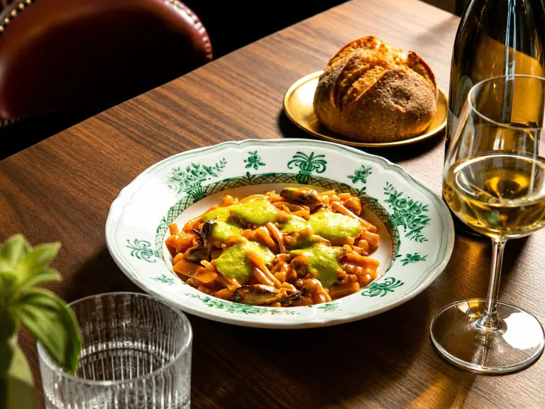 Piatto gourmet servito da Élevage Restaurant con calice di vino bianco sul tavolo