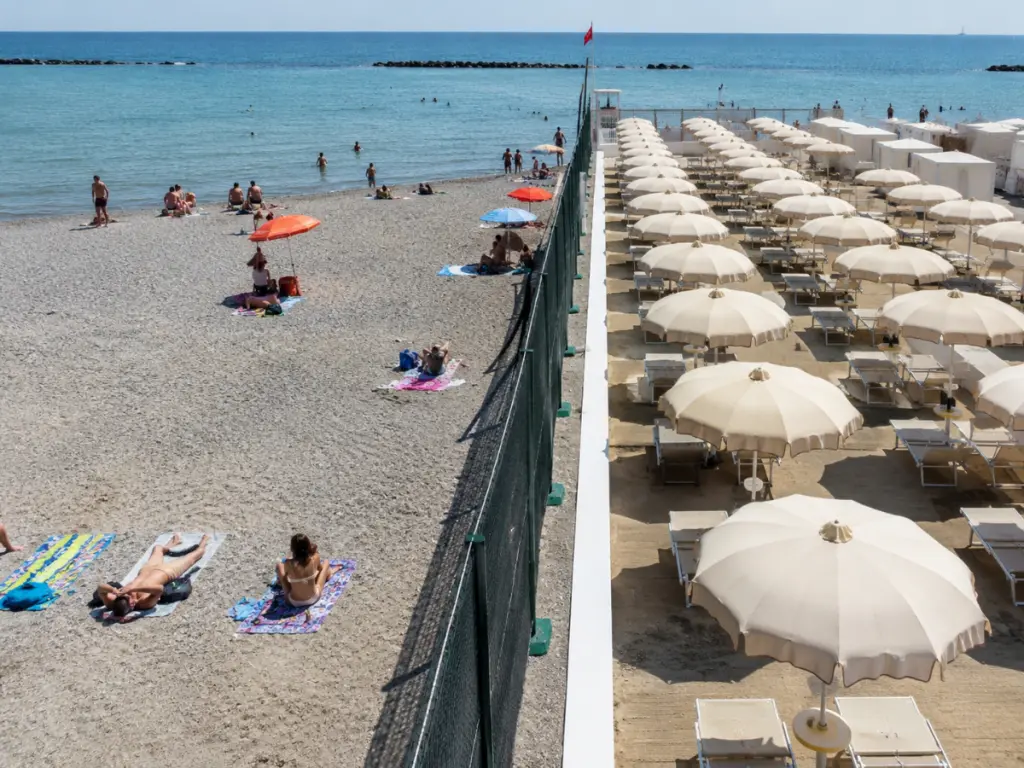 Una recinzione separa una spiaggia libera da uno stabilimento balneare su una costa italiana