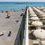 Una recinzione separa una spiaggia libera da uno stabilimento balneare su una costa italiana