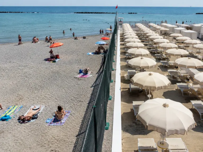 Una recinzione separa una spiaggia libera da uno stabilimento balneare su una costa italiana