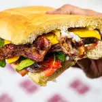 Panino extralarge con hamburger e patatine servito al Saloon del Panino sulla Portuense a Roma