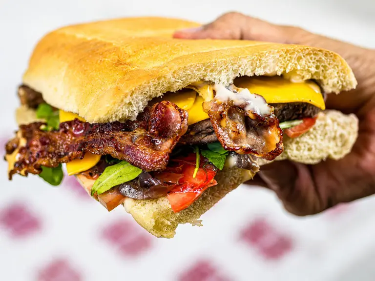 Panino extralarge con hamburger e patatine servito al Saloon del Panino sulla Portuense a Roma