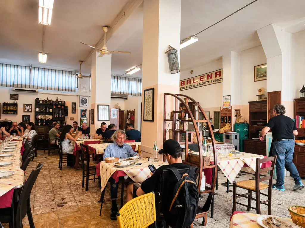 Persone in fila davanti alla trattoria Balena a Cagliari, celebre per il pesce del giorno e la cucina tradizionale