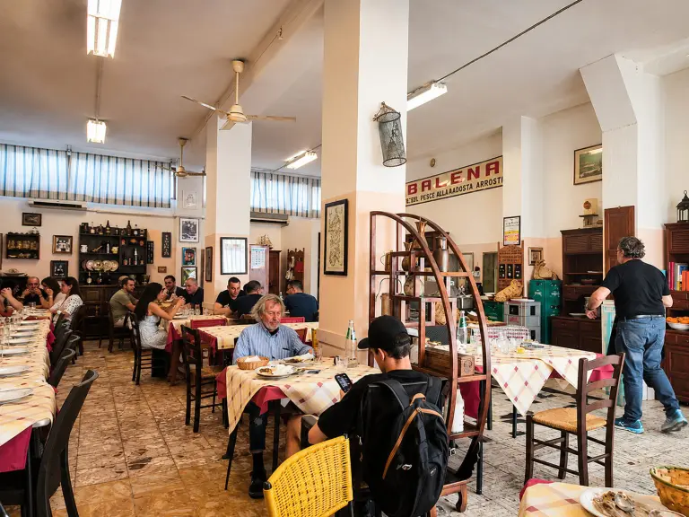 Persone in fila davanti alla trattoria Balena a Cagliari, celebre per il pesce del giorno e la cucina tradizionale