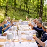 Cena di wild dining in una radura nel bosco con chef che cucinano sul fuoco vivo