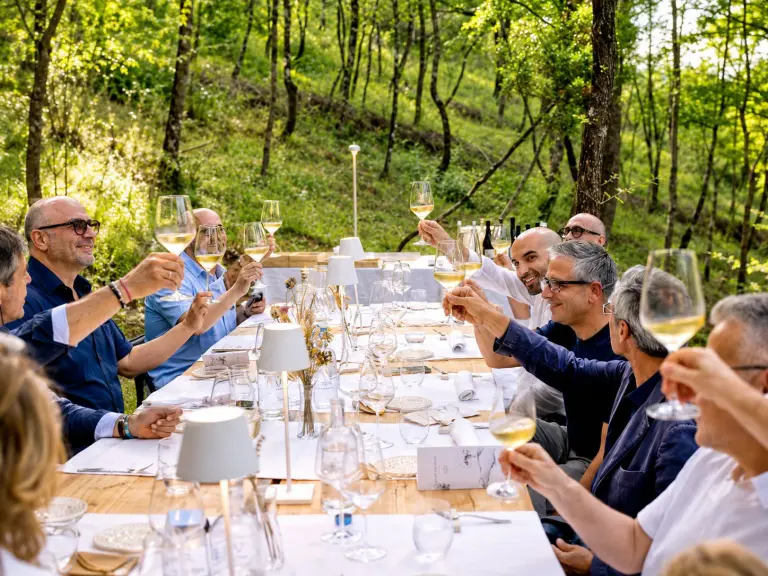 Cena di wild dining in una radura nel bosco con chef che cucinano sul fuoco vivo