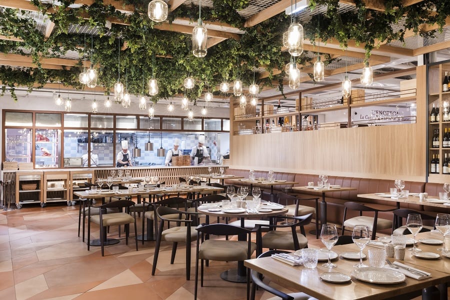Uno dei ristoranti di Eataly Parigi, con piante che scendono dal soffitto e tavoli in legno chiaro