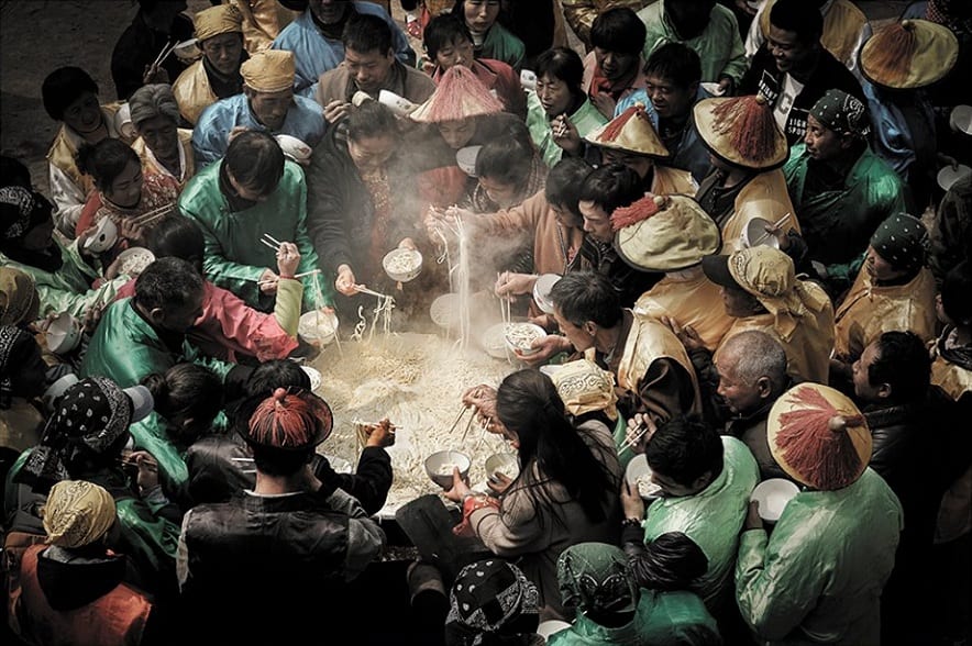 La spaghettata rituale in un villaggio cinese, in abiti tradizionali intorno a un calderone di noodle