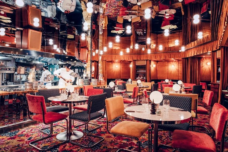 La sala di Gloria a Londra, con moquette rossa decorata, tavoli nudi, punti luce, soffitto specchiato, cucina a vista