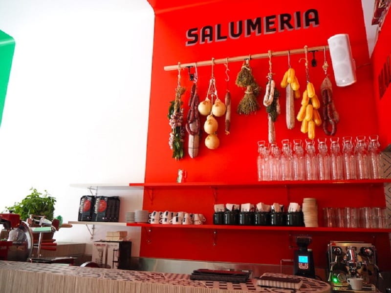 la parete rossa della slaumeria Mallozzi, con formaggi e salumi appesi
