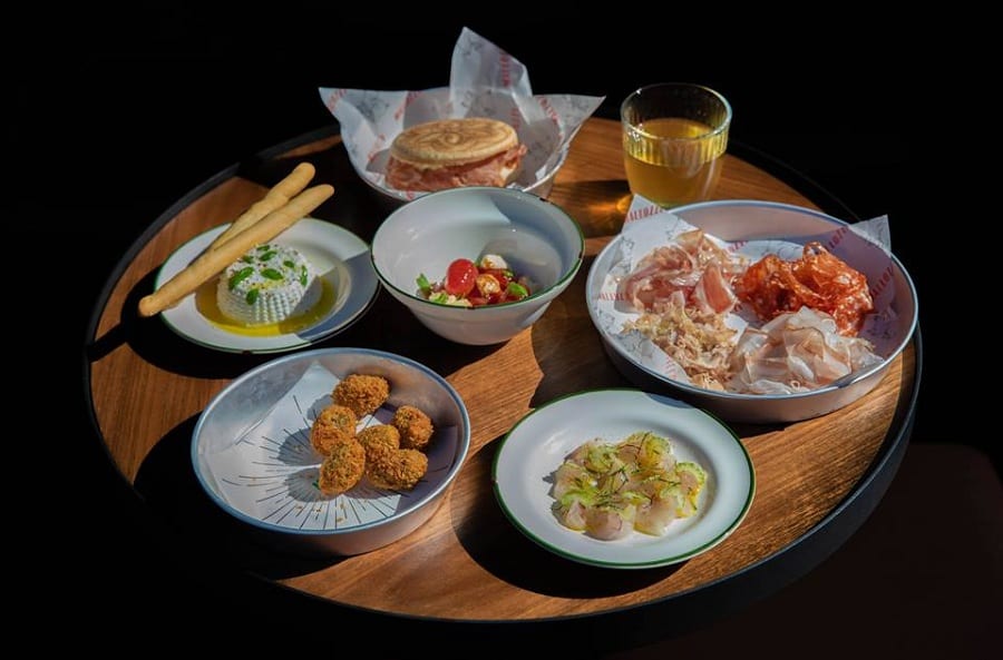 Sfizi di cucina italiana sulla tavola di Mallozzi: salumi, olive ascolane, ricotta, tigella con mortadella, insalata caprese
