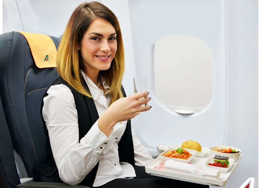 Una hostess di alitalia mangia seduta a bordo dell'aereo