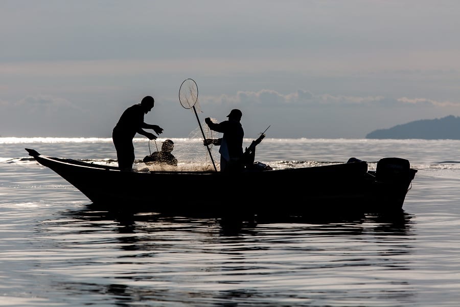 Tre pescatori in barca in controluce