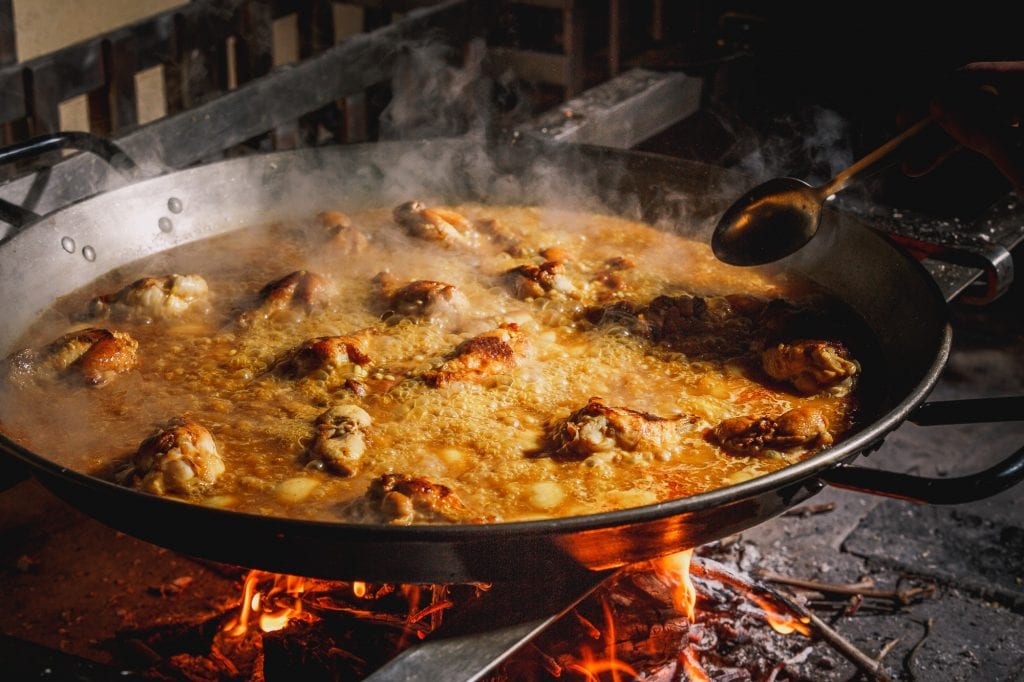 Una paella con riso in cottura su fuoco vivo