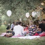 Immagine del pic nic Scamporella con i palloncini bianchi le persone sedute sul prato