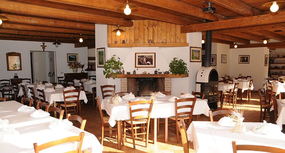 La sala del bioagriturismo Valle Scannese, con tavoli e boiserie in legno e camino