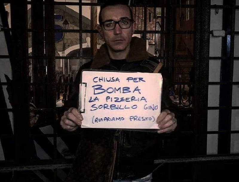 Gino Sorbillo con il cartello che denuncia l'intimidazione alla sua pizzeria di Napoli